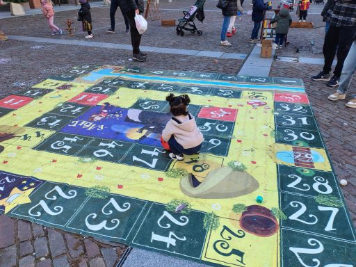 Bambina gioca su un grande gioco da tavolo colorato all'aperto.